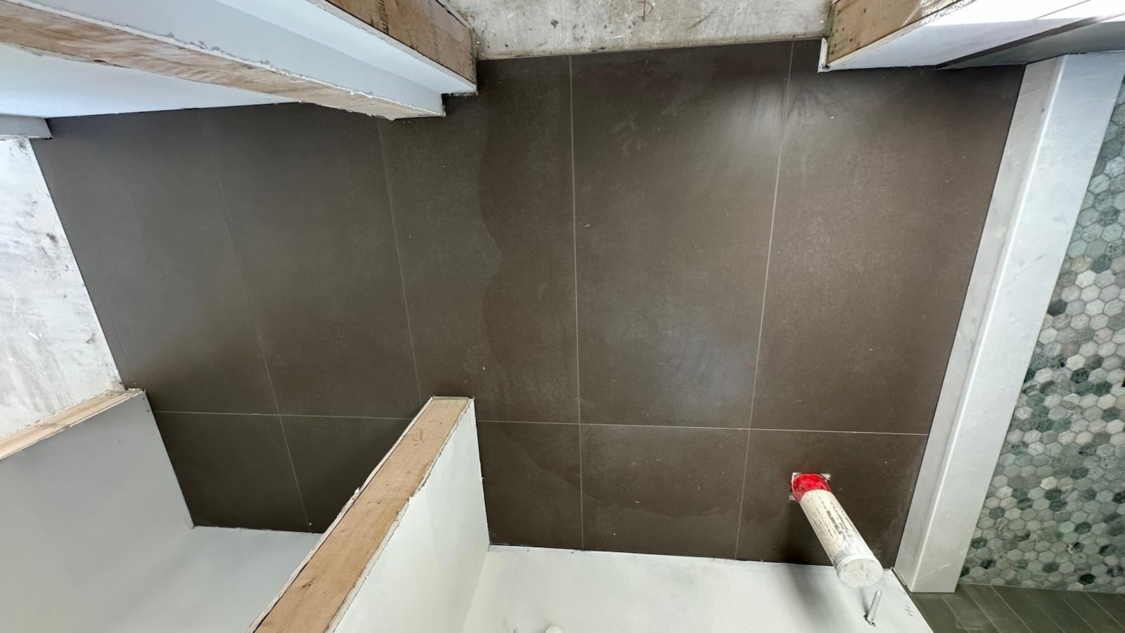 Large-format espresso brown tile shower wall with hexagon mosaic border