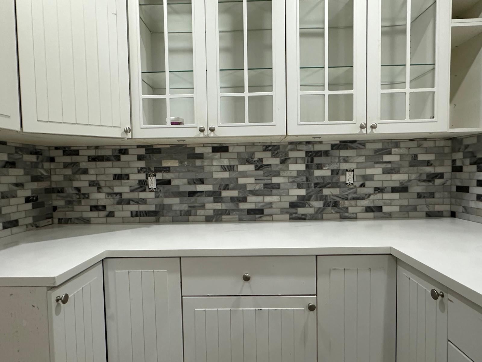 Gray and white stone mosaic kitchen backsplash under white cabinets